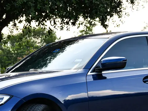 Morning light across the windshield and side glass of a blue sedan